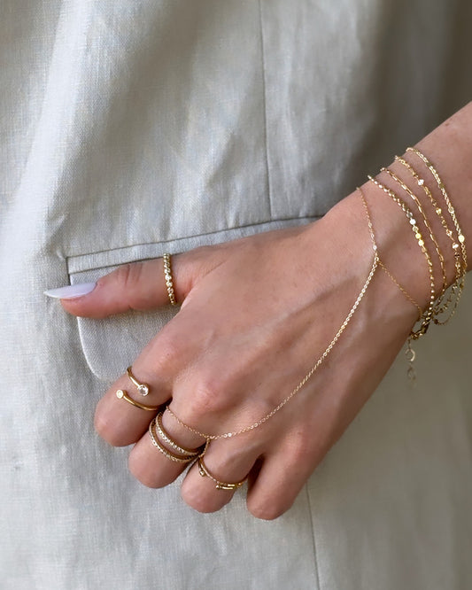 Model hand with dainty bracelets, minimalist hand chain and gold rings