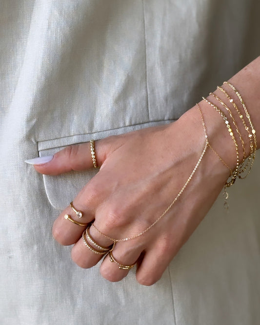 Model wearing dainty gold filled flat bead chain bracelet and other pieces from Dumai Jewelry