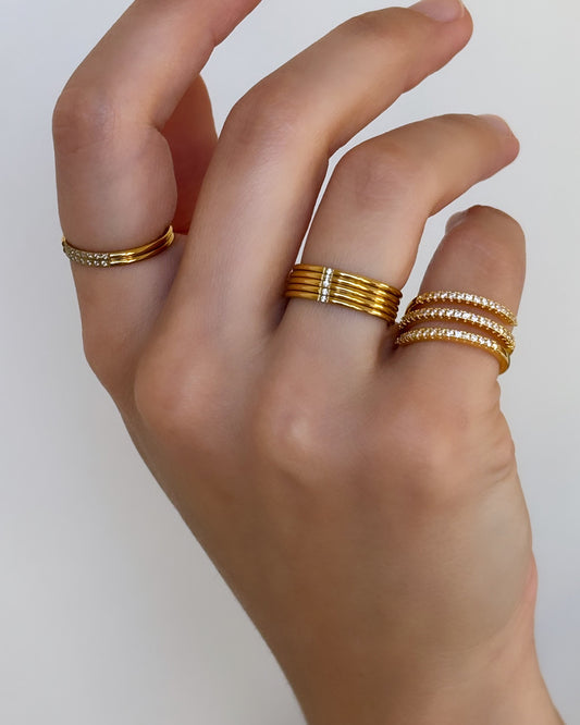 Model hand wearing stackable thin rings with stones and a spiral thin pave ring