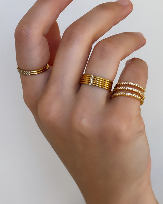Model hand wearing delicate and thin rings with stone details and a thin spiral studded ring