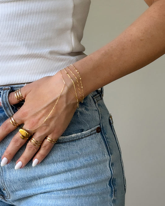 Model wearing rings with 2 or 3 polished bands, a statement ring and dainty bracelets.