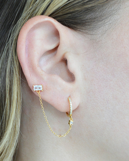 Model wearing gold plated double piercing chain hoop and emerald stud earring from Dumai Jewelry