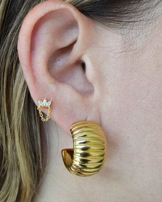Model wearing gold-plated half-flower chain stud earrings and ribbed hoops