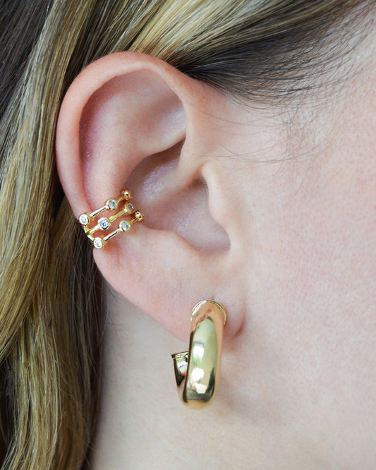 Model wearing gold filled triple layer ear cuff with round bezel accents and thick gold hoop from Dumai Jewelry