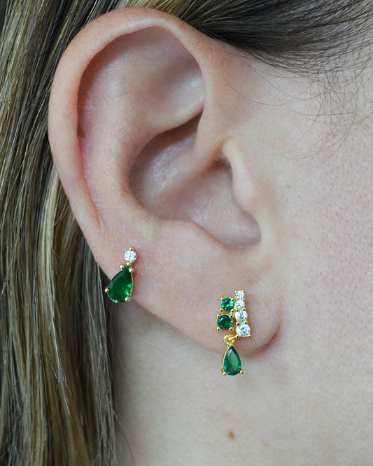 Model wearing gold-plated emerald teardrop studs and emerald and CZ studs