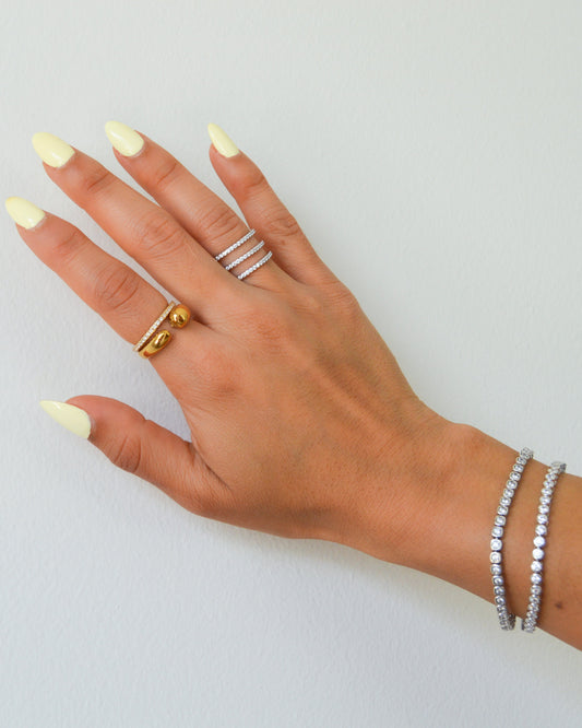 Vida Ring with three dainty pavé bands in sterling silver styled with a gold ring and tennis bracelets on a model hand
