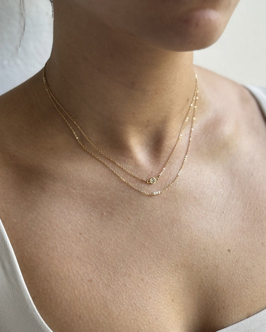 Model wearing dainty necklace stack