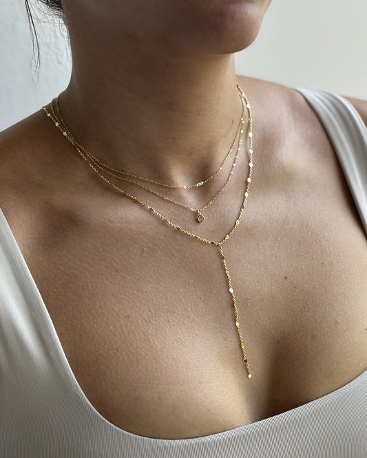 Model layering dainty gold necklaces