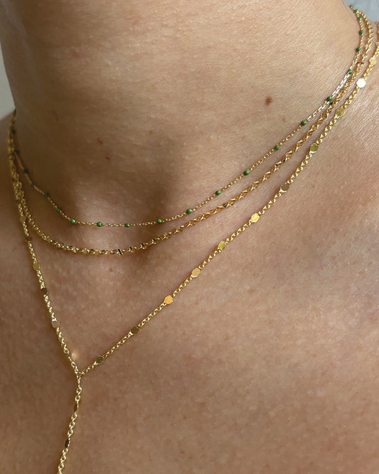 Model wearing dainty gold plated necklace stack