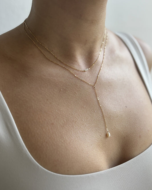 Model wearing dainty gold plated freshwater pearl lariat necklace and choker