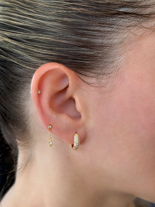 Model wearing 14K gold-coated sterling silver stud earrings featuring a delicate dangling chain with stud and a pave huggie