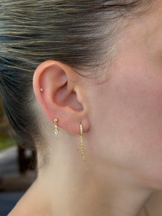 Dainty pavé chain huggie earrings in 14K gold-coated sterling silver and dangling CZ stud on model's ear