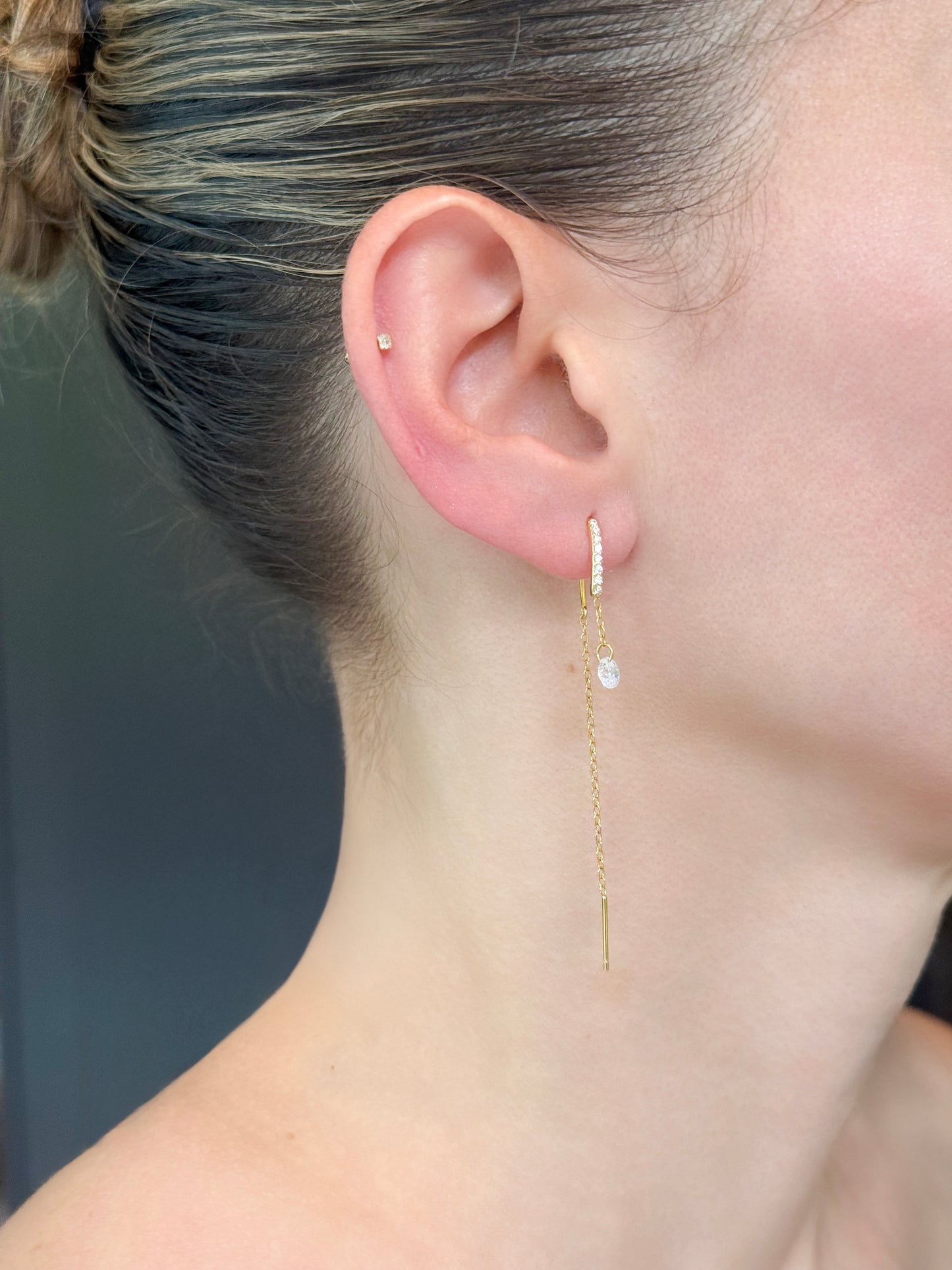 Gold plated threader earrings on model. Threaded through first piercing.