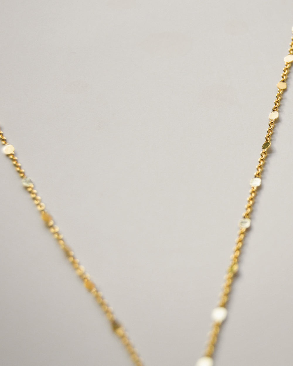 Close up of Gold filled dainty lariat necklace with reflective chain accents
